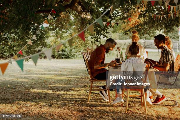 people having meal in garden - backyard party stock pictures, royalty-free photos & images