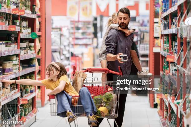 father with daughters doing shopping in supermarket - shopping cart stock-fotos und bilder