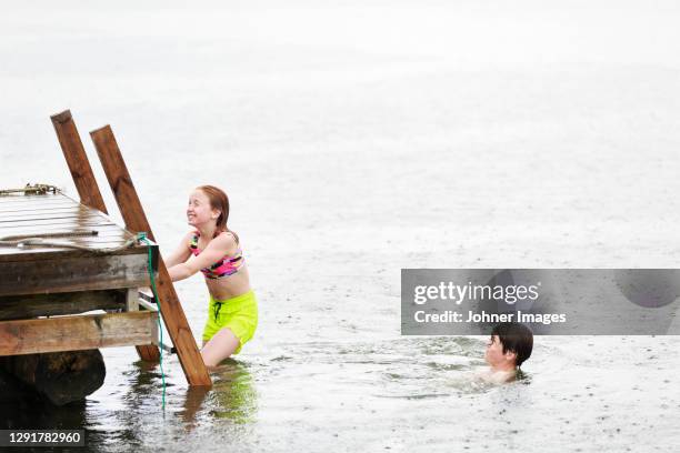 brother and sister at sea in rain - jetty stock pictures, royalty-free photos & images