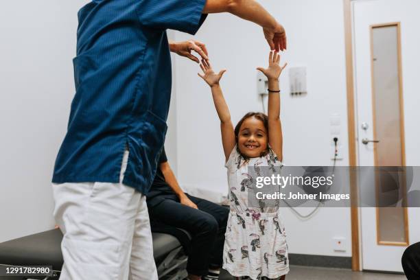 doctor examining girl in office - doctor arms raised stock pictures, royalty-free photos & images