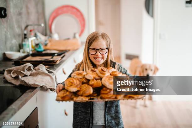 smiling girl holding tray with cinnamon buns - sweet bun stock-fotos und bilder