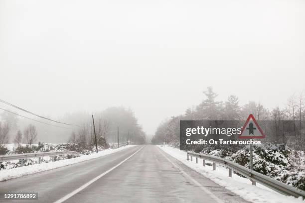 snowy and foggy road with a road signal - road signal ストックフォトと画像