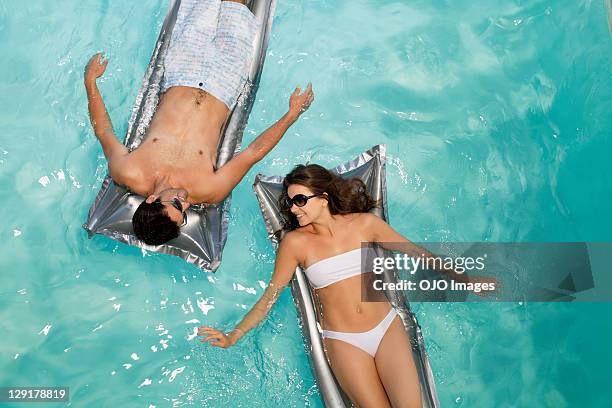 coppia sorridente in piscina galleggiante - mens swimwear foto e immagini stock