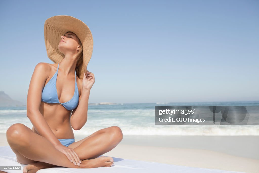Young woman in bikini sitting at beach