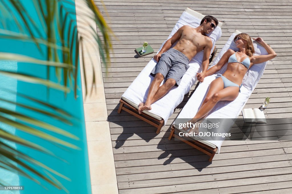 High angle view of smiling couple relaxing on deck chairs