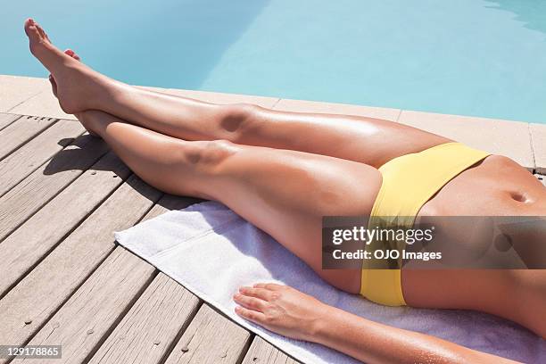 seção de baixa de mulher deitada de costas, próximo à piscina - women sunbathing - fotografias e filmes do acervo