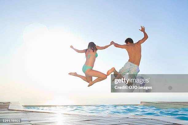 paar springen im schwimmbad gegen clear sky - jump in pool stock-fotos und bilder