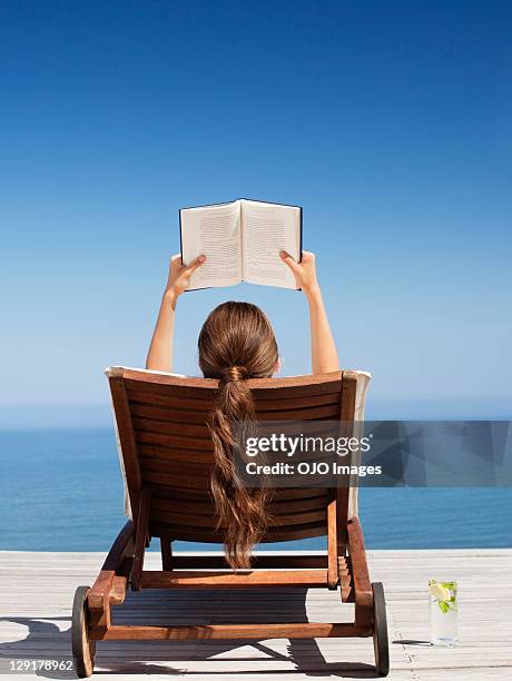 frau lesen buch im liegestuhl - frau liest buch sommer stock-fotos und bilder