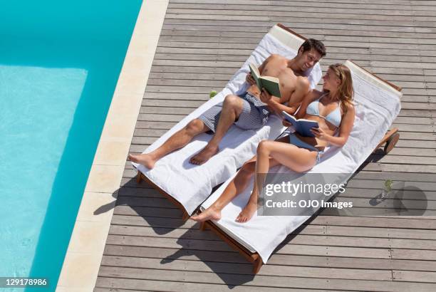 man and woman lying on deck chairs near swimming pool - deck chair 個照片及圖片檔