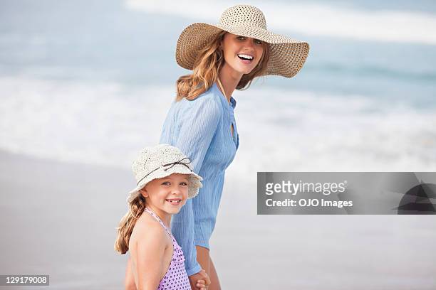 portrait of smiling mother and daughter at beach - sun hat stock pictures, royalty-free photos & images