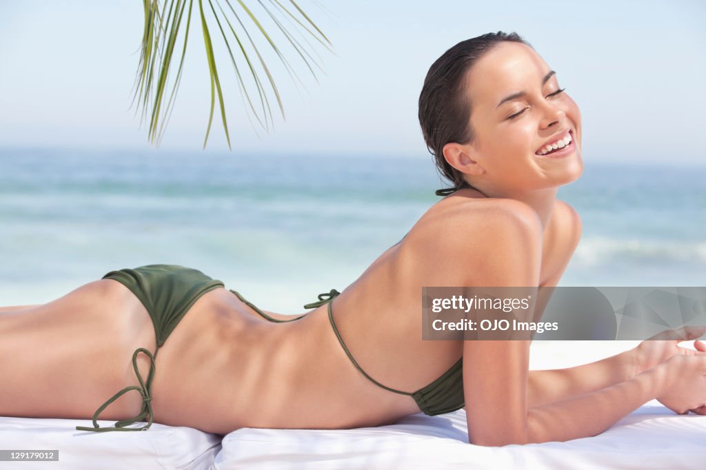 Smiling beautiful teenage girl lying on front at beach