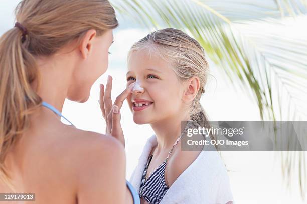 close-up of mother applying suntan lotion on daughter's nose - beautiful woman beach stock pictures, royalty-free photos & images