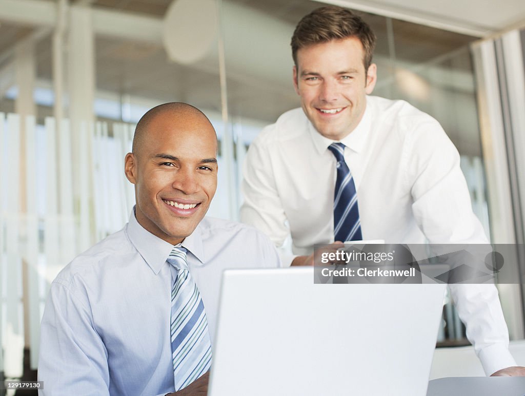 Businessmen smiling while using laptop