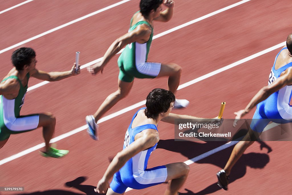 Male runners passing relay baton