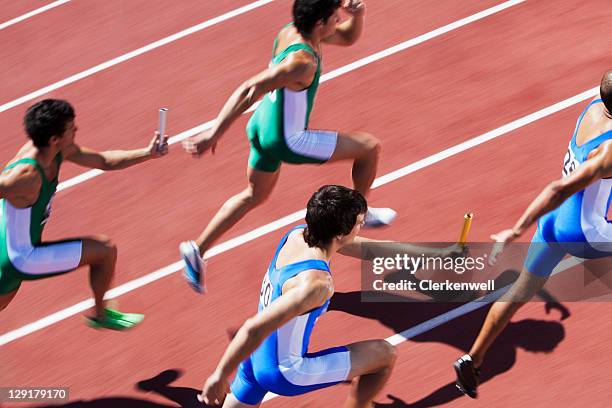 male runners passing relay baton - track and field stockfoto's en -beelden