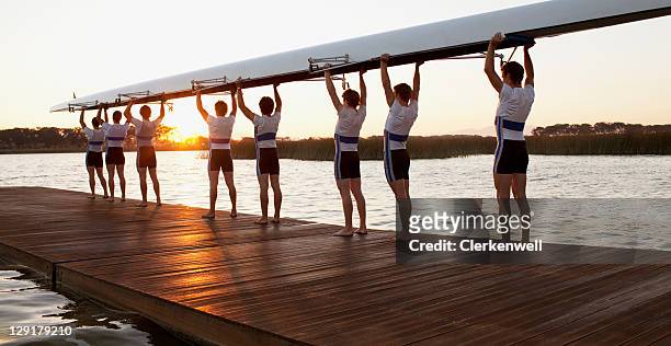 athletics carrying a crew canoe over heads - cooperazione foto e immagini stock