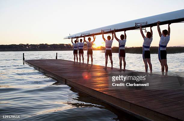 hombres sosteniendo canoa con cabezales - sports team fotografías e imágenes de stock