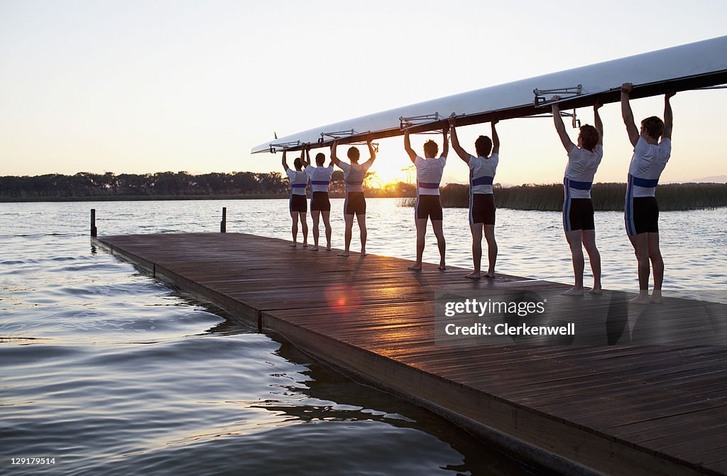 Homens segurando canoa mais de chefes