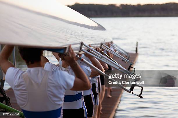 men carrying long canoe over hear - coxswain stock pictures, royalty-free photos & images