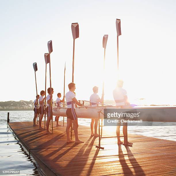 uomo in piedi sul molo con remo e canoa - sport di squadra foto e immagini stock