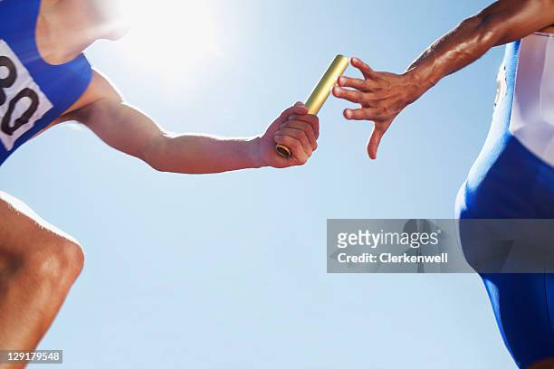 runner passing baton during relay event - athletics team stock pictures, royalty-free photos & images
