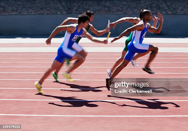 male athlete running with relay baton - track and field event stock pictures, royalty-free photos & images