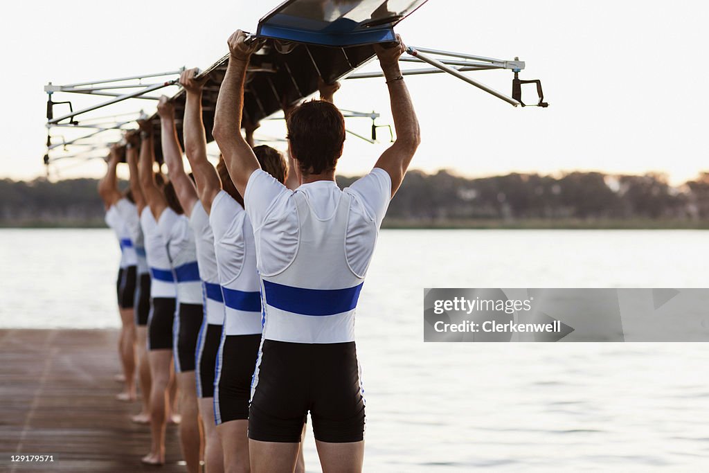 Team of rowers carrying a crew canoe over heads