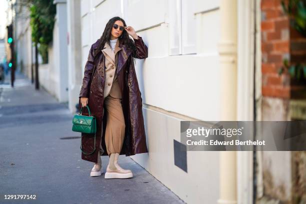 Gabriella Berdugo wears sunglasses, a white turtleneck pullover, earrings, a necklace, a bi color beige and brown oversized blazer jacket and suit...
