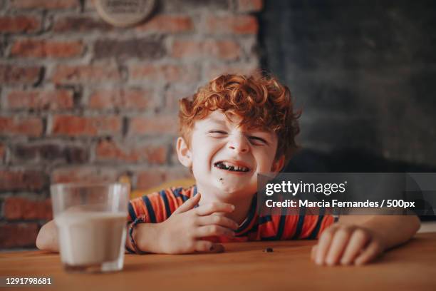 young caucasian boy eating a chocolate cookie with milk - eating cookies foto e immagini stock