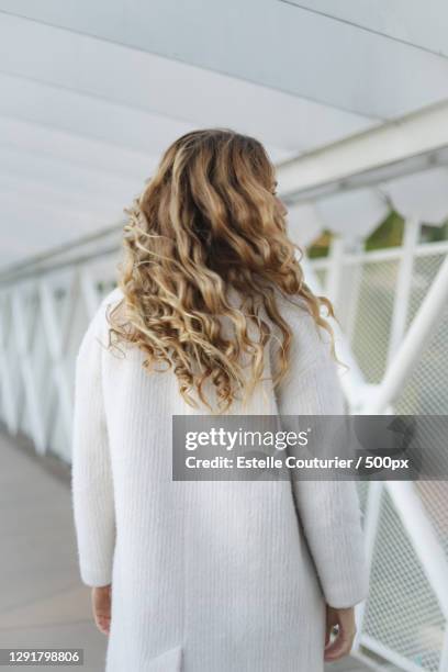 rear view of woman standing against fence,france - curly hair back stock pictures, royalty-free photos & images