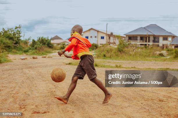 young african boy walking through village with soccer ball,tema,ghana - africa game stock-fotos und bilder