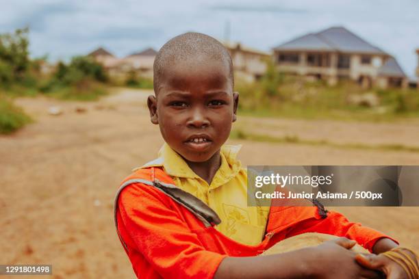 young african boy walking through village with soccer ball,tema,ghana - portrait afrika kind stock-fotos und bilder