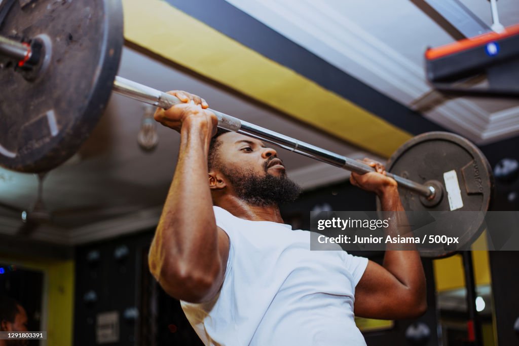 Young man exercising with barbell in gym
