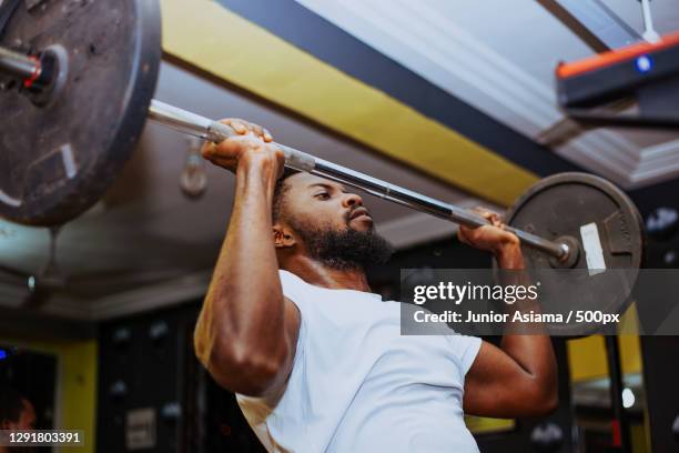 young man exercising with barbell in gym - black male bodybuilders stock pictures, royalty-free photos & images