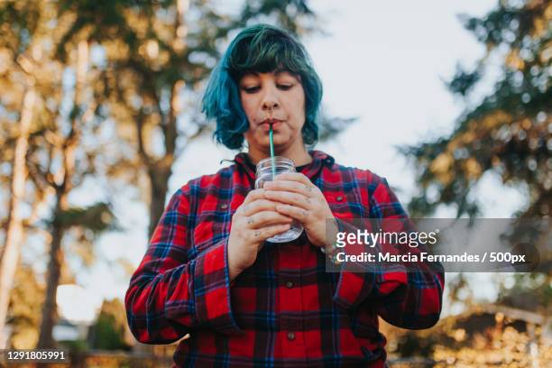 woman using reusable stainless steel straw outdoors during sunset,victoria,british columbia,canada - metal straw stock pictures, royalty-free photos & images