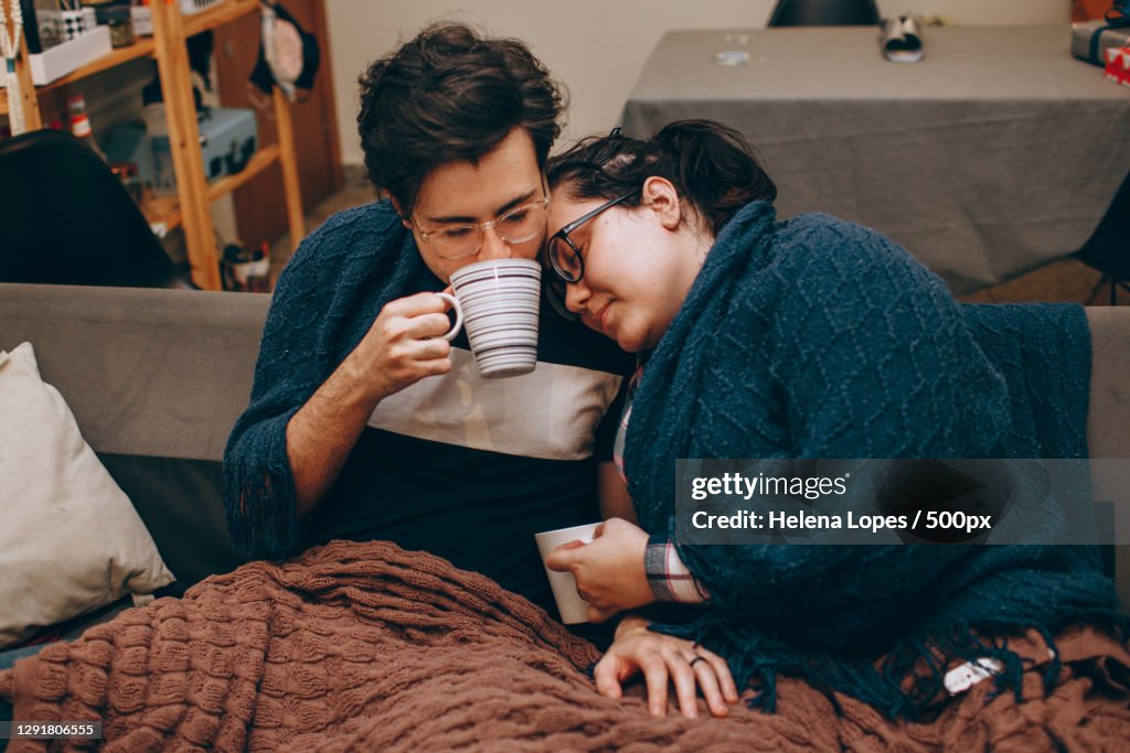 Young adult couple sharing a cozy night in together at home with hot drinks