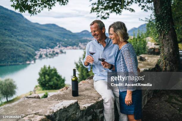 het rijpe paar geniet van wat rode wijn in italiaanse wijngaard - luxury destinations stockfoto's en -beelden