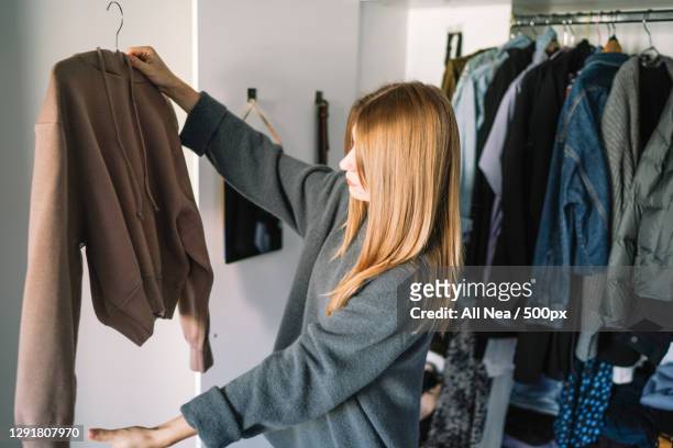 caucasian woman organizing closet at home,spain - winter coats stockfoto's en -beelden