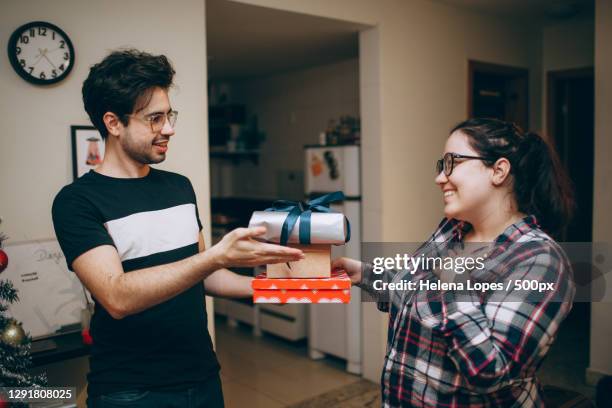 young adult brazilian couple exchanging christmas holiday gifts - exchanging gift stock pictures, royalty-free photos & images