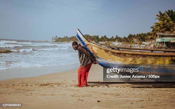 man hauling fishing boat into the ocean,accra,ghana - accra stock pictures, royalty-free photos & images