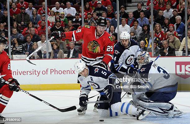 Bryan Bickell of the Chicago Blackhawks pushes into Mark Stuart of the Winnipeg Jets, as Michael Frolik of the Blackhawks rushes in from the side to...