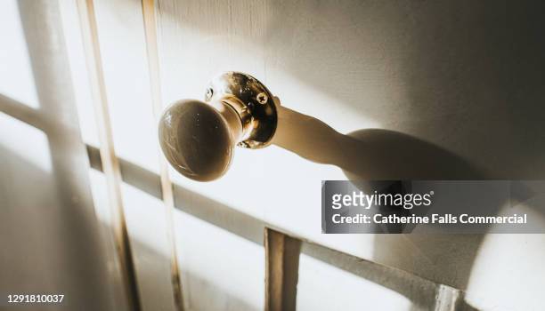 abstract image of an old door knob casting a shadow on an old wooden door - stuck indoors stock pictures, royalty-free photos & images