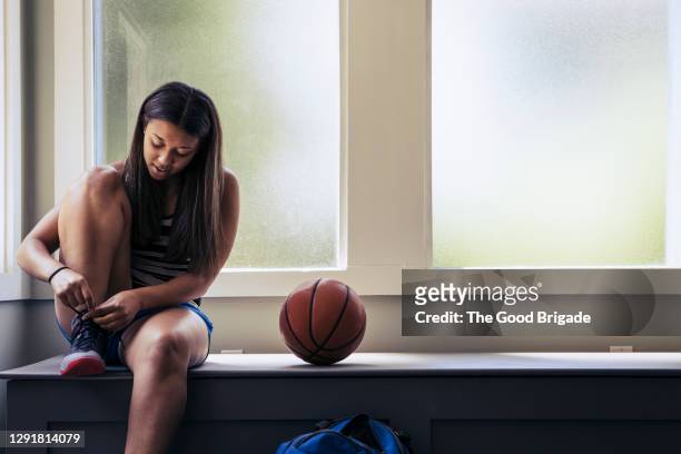 teenage girl tying shoe preparing to play basketball - girl dressing up stock pictures, royalty-free photos & images