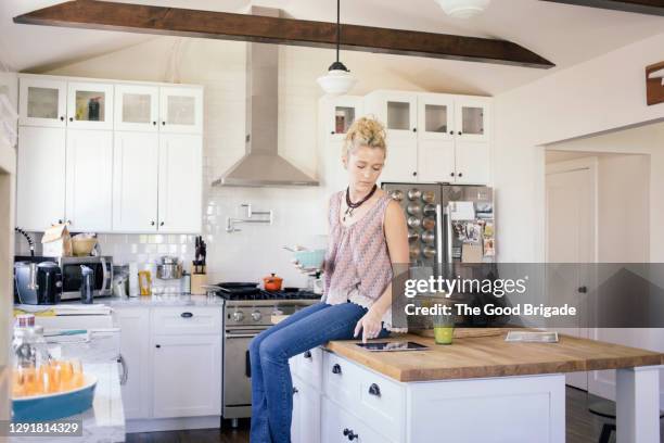 young woman using digital tablet in kitchen at home - kitchen island ストックフォトと画像