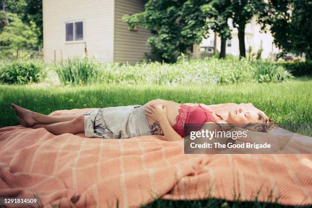 pregnant woman lying on blanket in backyard - moment of silence stockfoto's en -beelden