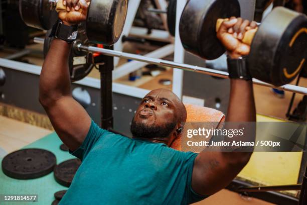 young man lifting barbell in gym,tema,ghana - workout bench stock pictures, royalty-free photos & images