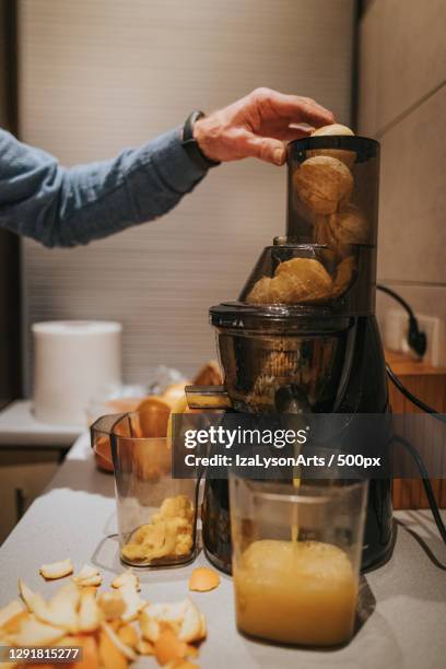 senior man using juicer to make orange juice,poland - saftpresse stock-fotos und bilder