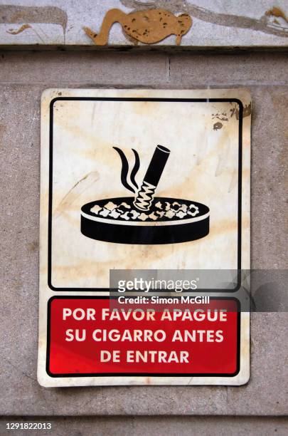 spanish-language sign on a building exterior stating 'por favor apague su cigarro antes de entrar' [please extinguish your cigar before entering] - entrar stockfoto's en -beelden