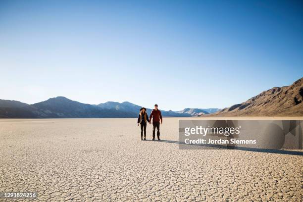 a couple holding hands while hiking in the racetracks region of death valley - nevada stock-fotos und bilder