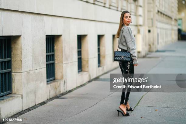 Maria Rosaria Rizzo wears golden earrings, a gray wool pullover from Tularosa, a black quilted Chanel bag, golden bracelets and jewelry, black shiny...